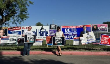 A group of people are seen holding up campaign signs during a runoff election on a sunny day in San Antonio, Texas.