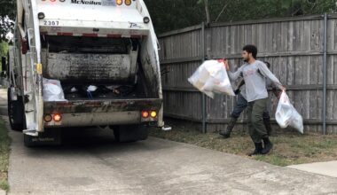 A man throwing two trash bags into the back of a garbage truck