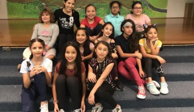 Monica Chin smiles for a photo with a group of young female dance students