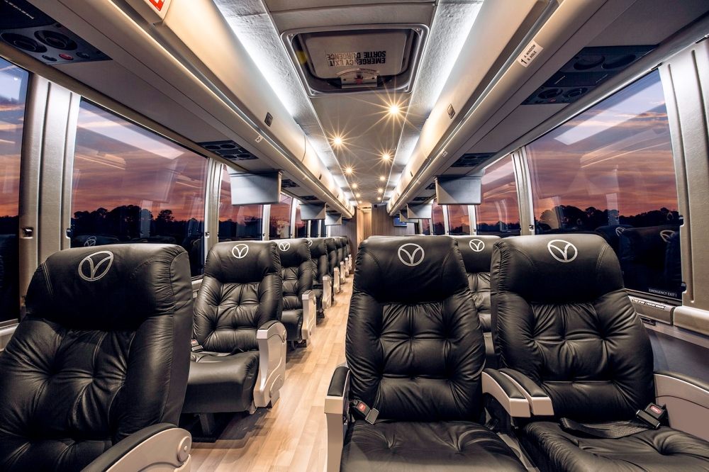 A view down the aisle of a bus with cushioned black leather seats