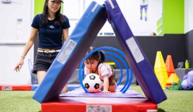 A toddler pushes a soccer ball through an obstacle course while a woman observes
