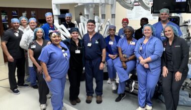 Medical City McKinney medical officials and leaders pose in front of a new surgical robot after completing its first operation.