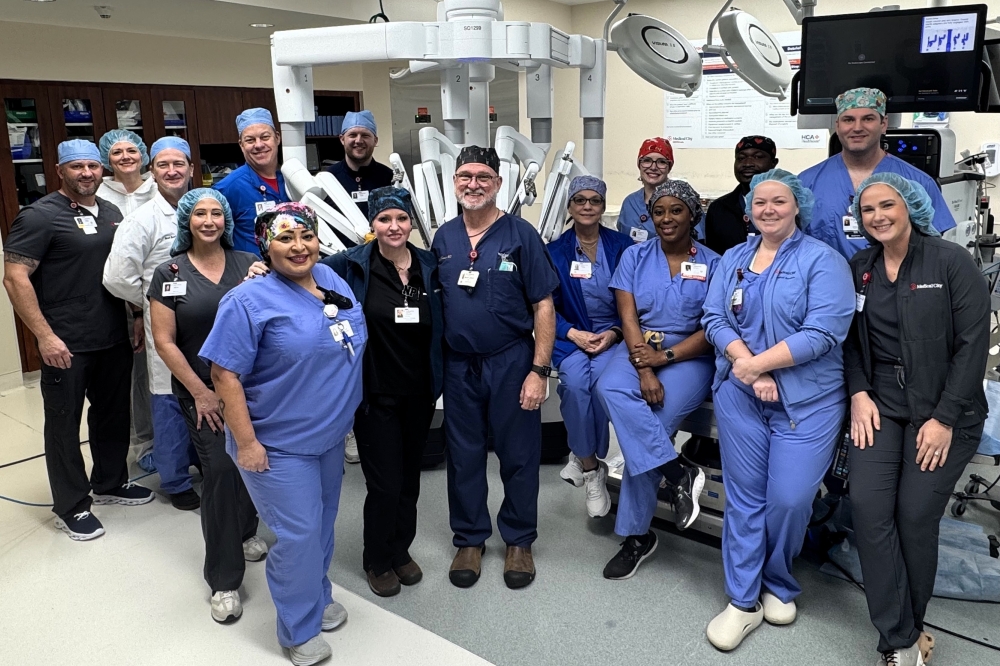 Medical City McKinney medical officials and leaders pose in front of a new surgical robot after completing its first operation.