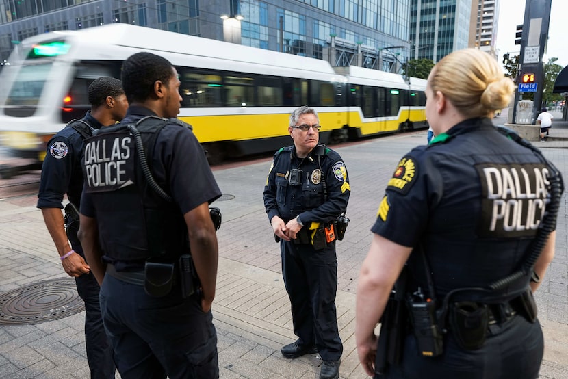 Dallas police who are part of a Downtown task force talk with DART police officers at the...