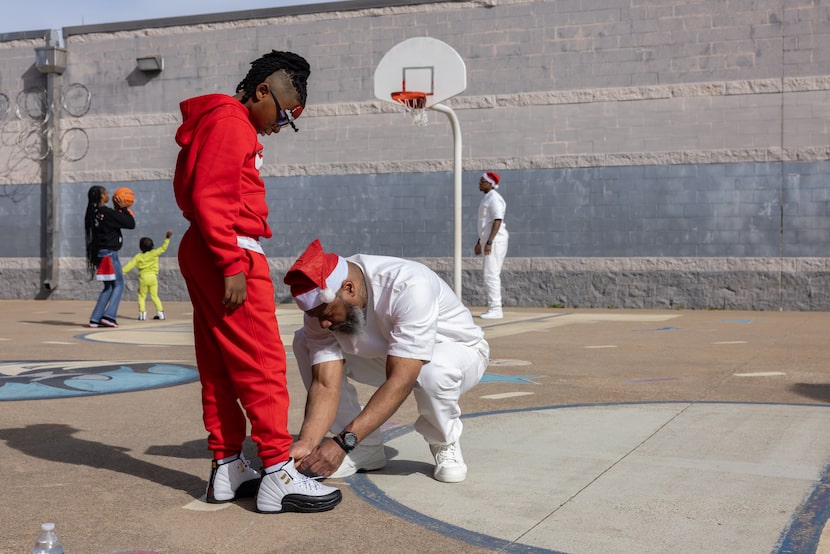 Kevin Porter ties the shoelaces of his son, Levi, during a Chirstmas with dads event at the...