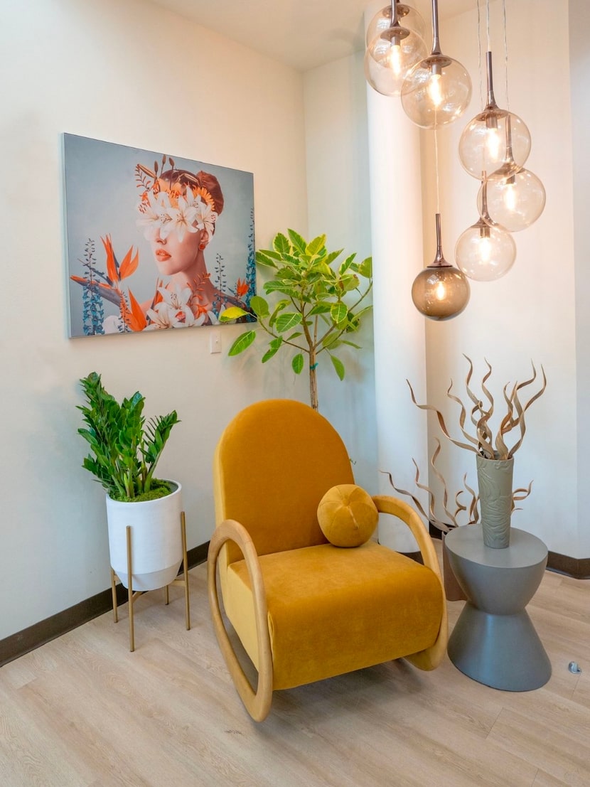 white walls with a yellow velvet chair, a great chandelier, and a colorful painting of a woman