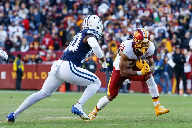 Dec 25, 2025; Landover, Maryland, USA; Washington Commanders running back Jeremy McNichols (26) carries the ball defended by Dallas Cowboys linebacker Shemar James (50) in the second quarter at Northwest Stadium. Mandatory Credit: Amber Searls-Imagn Images