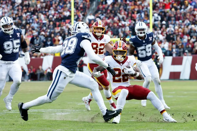 Dec 25, 2025; Landover, Maryland, USA; Washington Commanders running back Jacory Croskey-Merritt (22) carries the ball defended by Dallas Cowboys safety Malik Hooker (28) in the third quarter at Northwest Stadium. Mandatory Credit: Amber Searls-Imagn Images