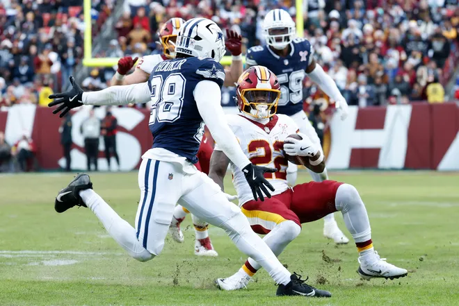 Dec 25, 2025; Landover, Maryland, USA; Washington Commanders running back Jacory Croskey-Merritt (22) carries the ball defended by Dallas Cowboys safety Malik Hooker (28) in the third quarter at Northwest Stadium. Mandatory Credit: Amber Searls-Imagn Images