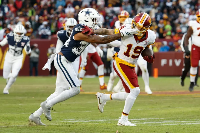Dec 25, 2025; Landover, Maryland, USA; Washington Commanders wide receiver Chris Moore (19) carries the ball after a reception defended by Dallas Cowboys cornerback Shavon Revel Jr. (34) in the third quarter at Northwest Stadium. Mandatory Credit: Geoff Burke-Imagn Images