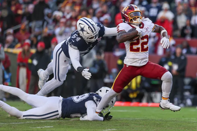 LANDOVER, MARYLAND - DECEMBER 25: Jacory Croskey-Merritt #22 of the Washington Commanders runs against Malik Hooker #28 and Sam Williams #54 of the Dallas Cowboys in the second quarter of a game at Northwest Stadium on December 25, 2025 in Landover, Maryland. (Photo by Scott Taetsch/Getty Images)