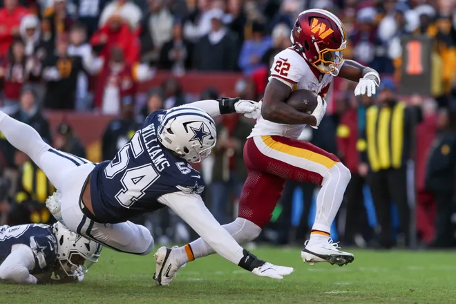 LANDOVER, MARYLAND - DECEMBER 25: Jacory Croskey-Merritt #22 of the Washington Commanders runs against Malik Hooker #28 and Sam Williams #54 of the Dallas Cowboys in the second quarter of a game at Northwest Stadium on December 25, 2025 in Landover, Maryland. (Photo by Scott Taetsch/Getty Images)