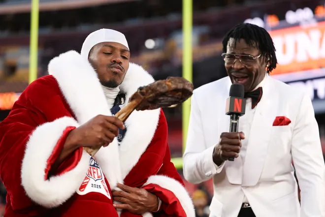 LANDOVER, MARYLAND - DECEMBER 25: Trevon Diggs #7 of the Dallas Cowboys eats a steak as Michael Irvin reacts after Dallas' 30-23 victory against the Washington Commanders at Northwest Stadium on December 25, 2025 in Landover, Maryland. (Photo by Scott Taetsch/Getty Images)