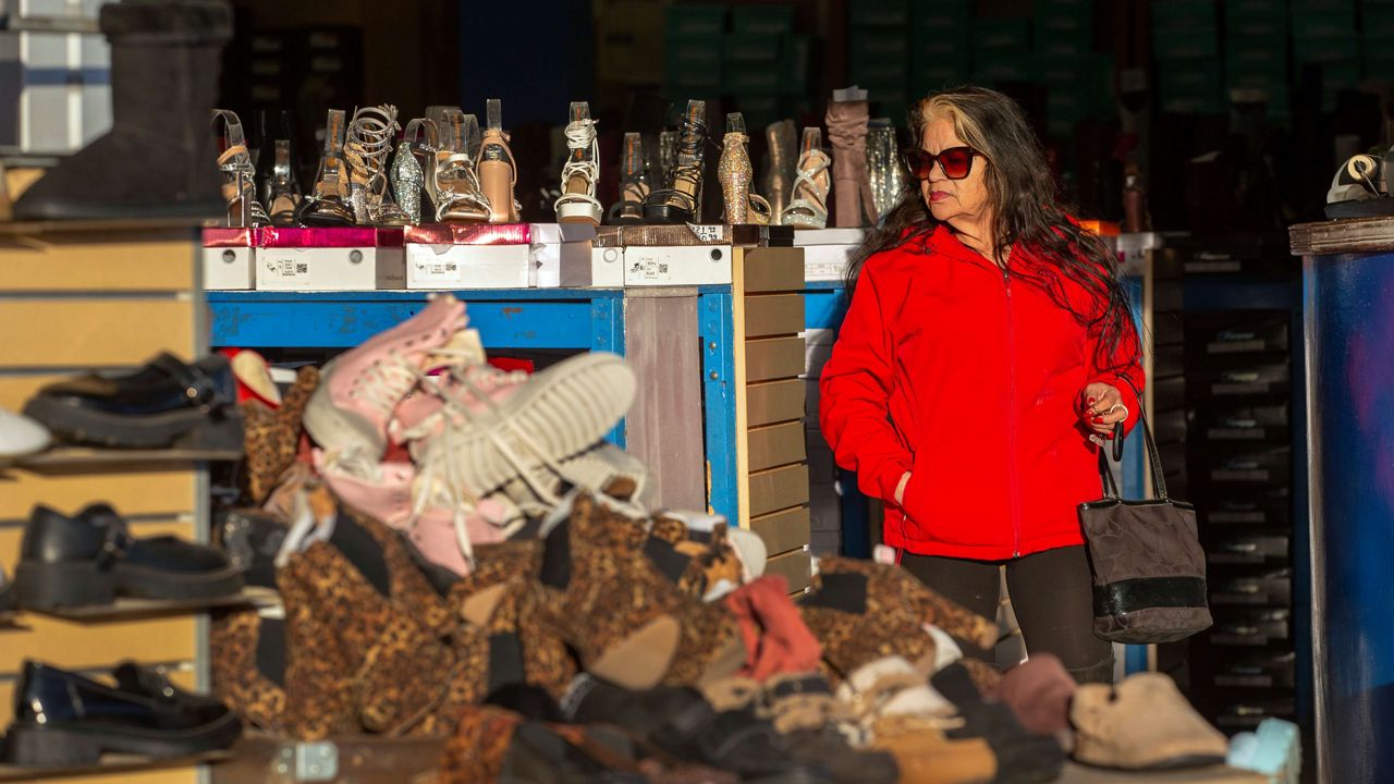 A woman shops for shoes at a store across the Paso del Norte bridge that connects Ciudad Juarez, Mexico, with downtown El Paso, Sunday, Jan. 19, 2025, in El Paso, Texas. (AP Photo/Andres Leighton)