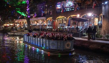 A group in Santa hats ride a barge as they view holiday lights along the Riverwalk, Wednesday, Dec. 3, 2025, in San Antonio. (AP Photo/Eric Gay)