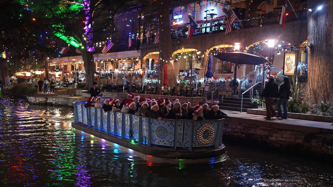 A group in Santa hats ride a barge as they view holiday lights along the Riverwalk, Wednesday, Dec. 3, 2025, in San Antonio. (AP Photo/Eric Gay)