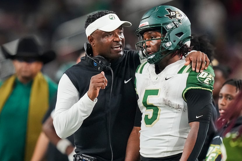 DeSoto head coach Claude Mathis talks with running back Sarod Baker (5) on the sidelines...