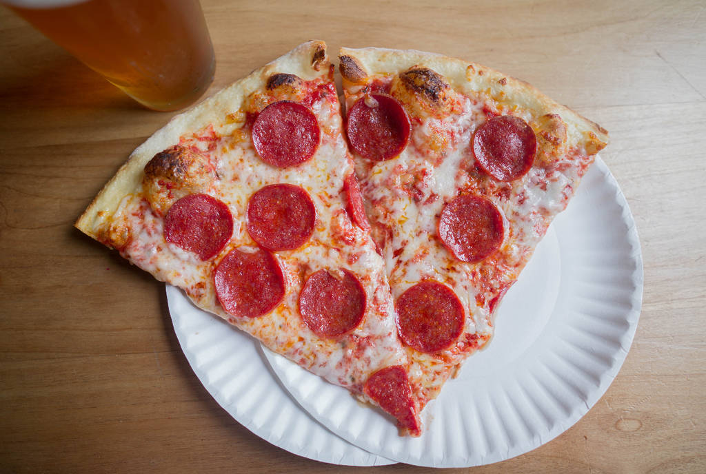 Image shows a pepperoni pizza on a paper plate.