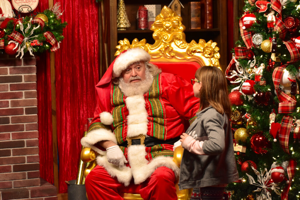 Image shows Santa Claus speaking with a little girl.