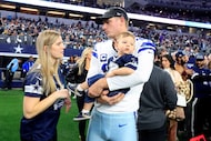 Dallas Cowboys place kicker Brandon Aubrey holds his son Colton as he visits with his wife...
