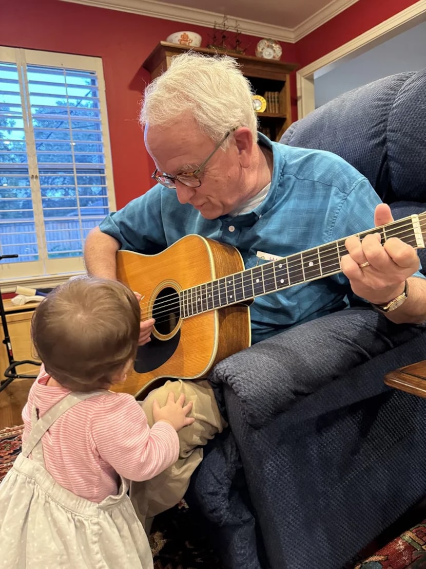 Charles Hosch plays guitar for his granddaughter.