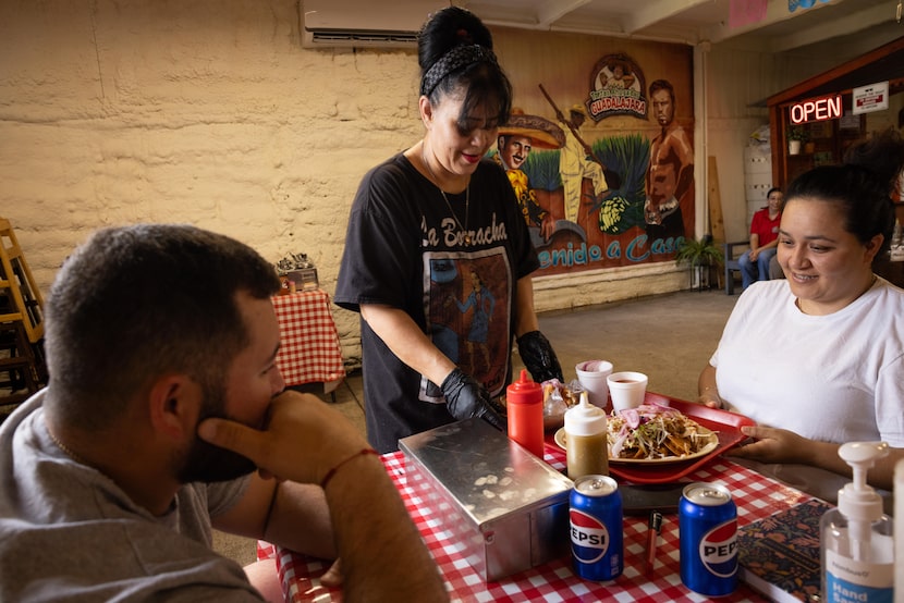 Doña Ana Nieto sets down tacos dorados for customers Jairo Gonzalez and Ana Rodriguez at...