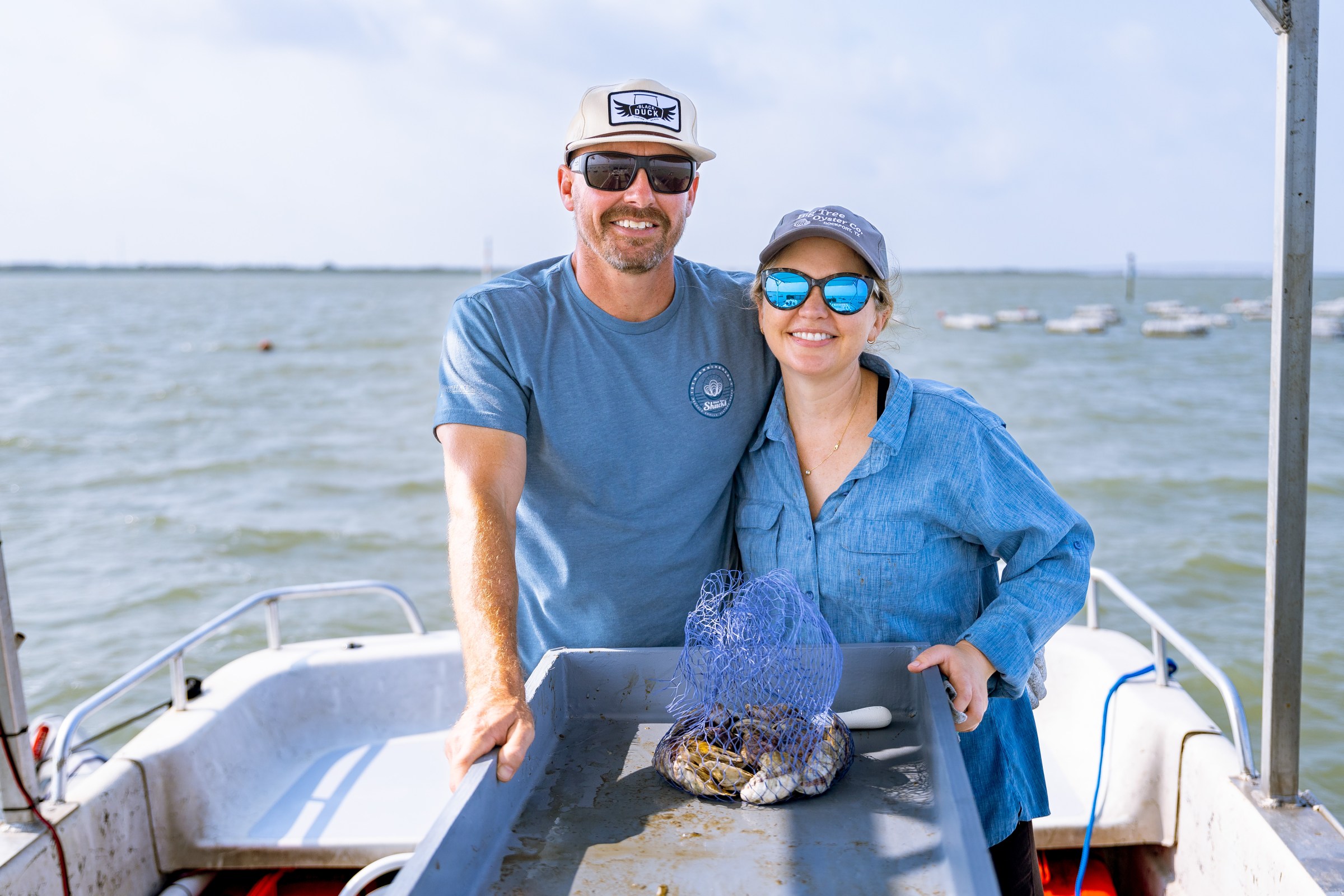 A married couple in blue shirts farming oysters.