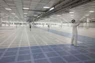 Employees wear smocks and safety gear inside a cleanroom at Texas Instruments' new...