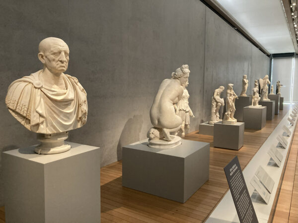 A photograph of a row of marble sculptures of various people.