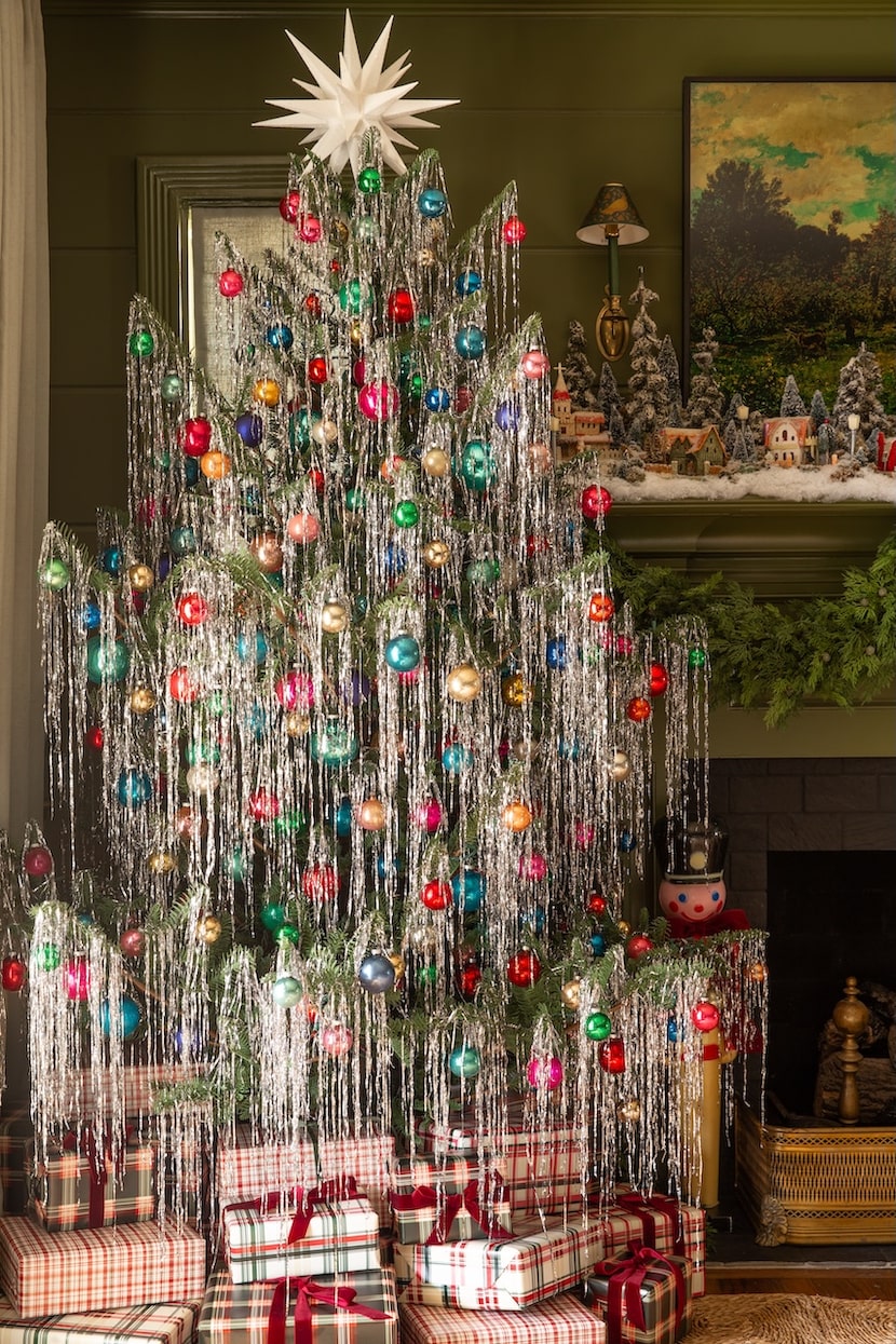 Tinsel-colored tree with multicolored ornaments and gifts beneath the tree