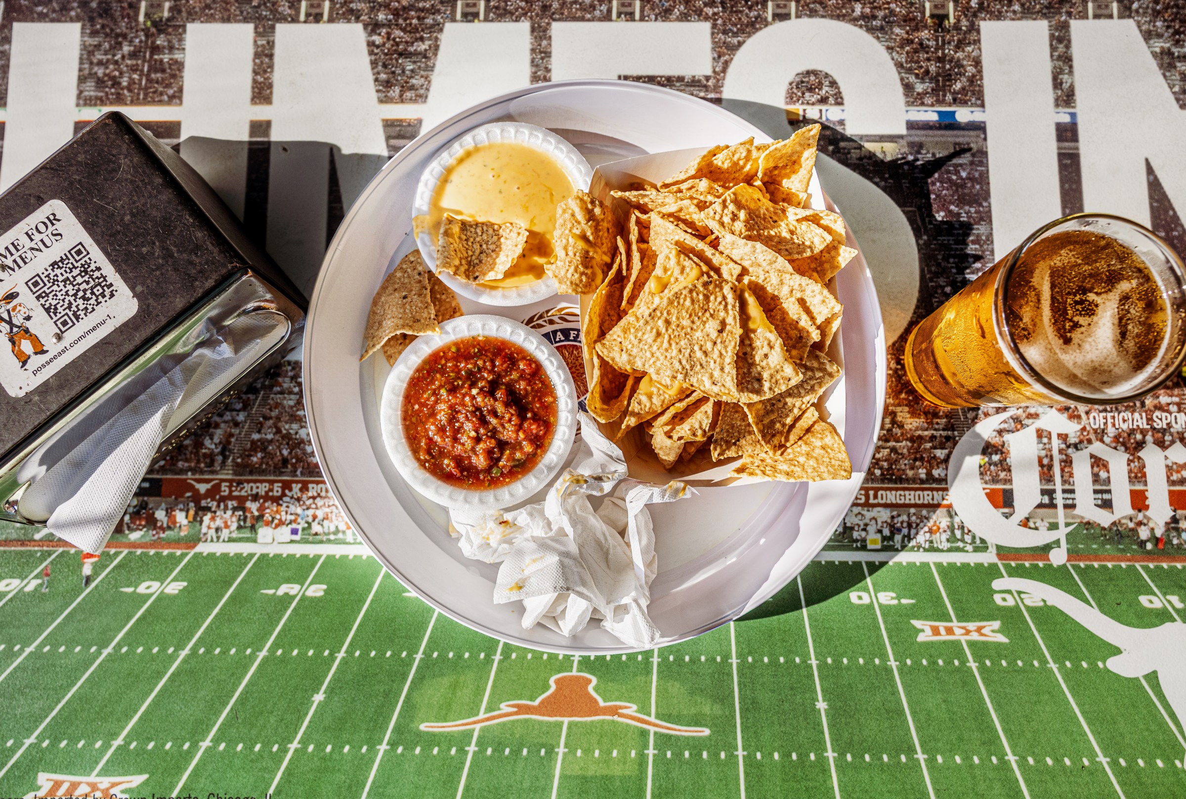 Chips and dip on a table with a football field as artwork.