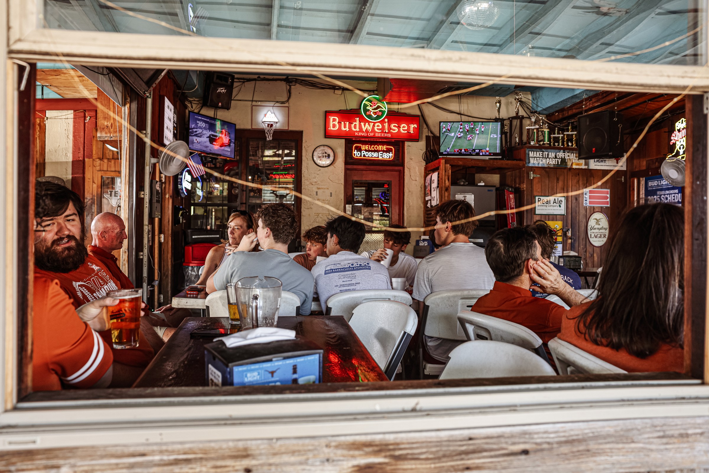 Patrons sit at a bar and watch football. 