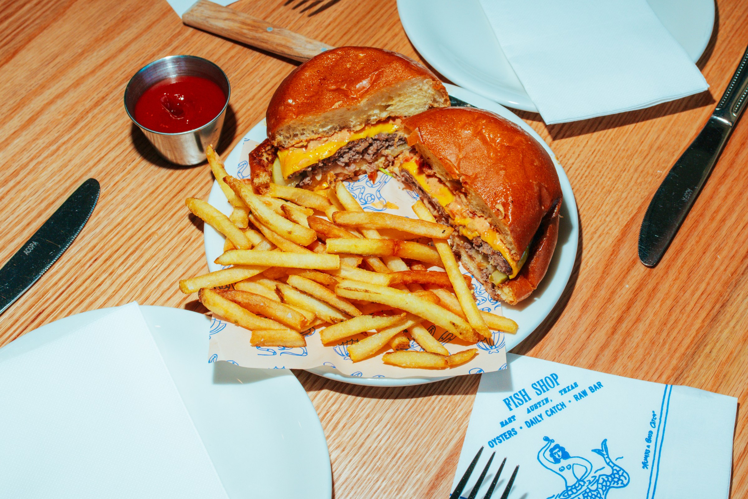 A burger on a wooden table with fries and ketchup. 