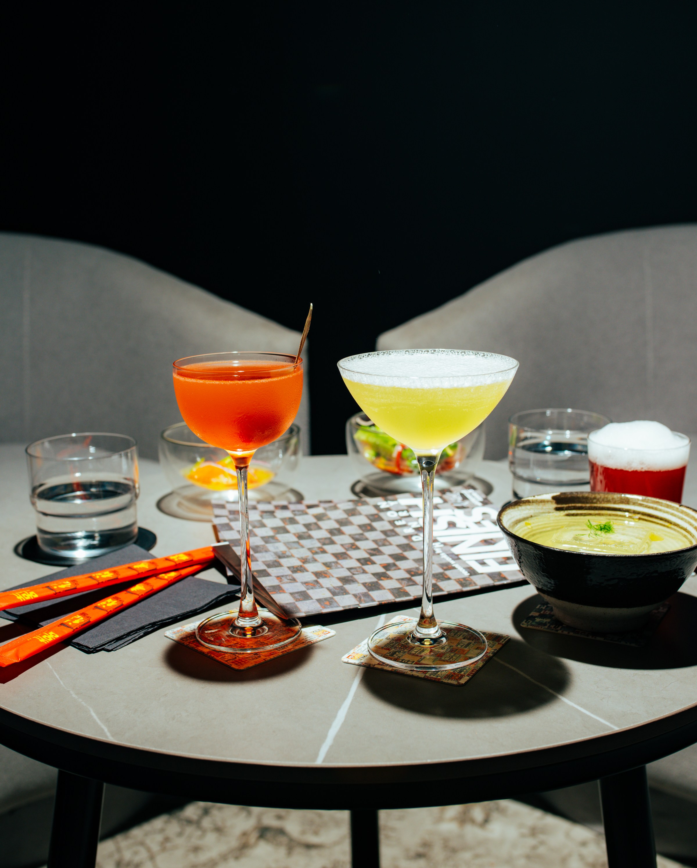 Drinks on a black table, one of which is in a bowl.