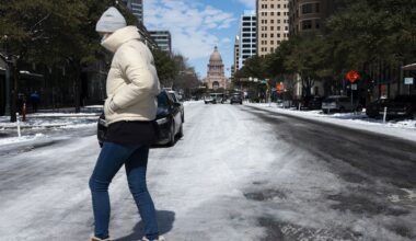 A woman walks across the snow covered street near the Texas state capitol Tuesday, Feb. 16, 2021, in Austin, Texas. (AP Photo/Ashley Landis)
