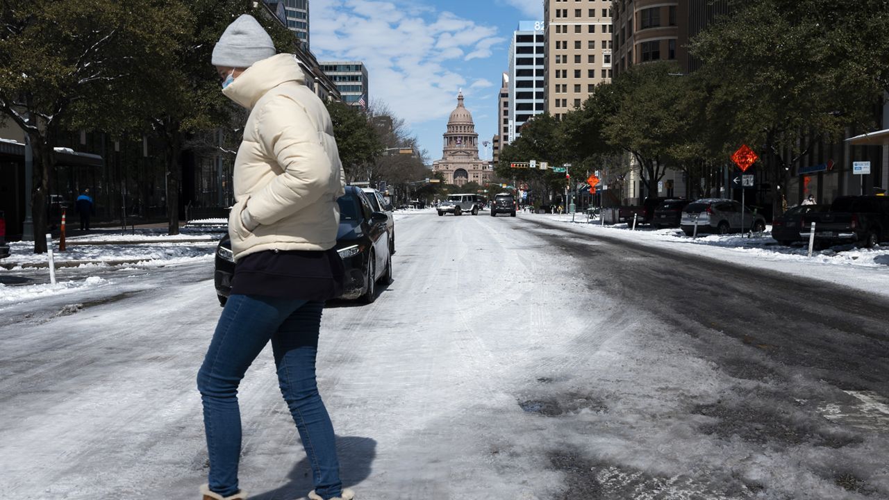 A woman walks across the snow covered street near the Texas state capitol Tuesday, Feb. 16, 2021, in Austin, Texas. (AP Photo/Ashley Landis)