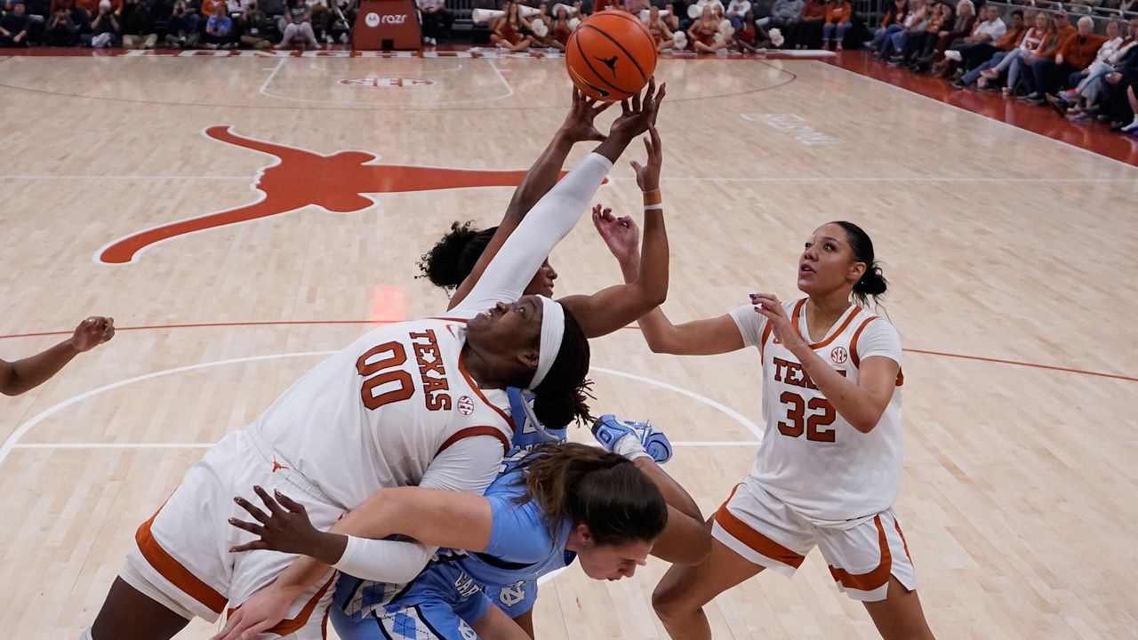 Texas center Kyla Oldacre (00) battles North Carolina guard Indya Nivar, rear, and forward Ciera Toomey, center, for a rebound during the second half of an NCAA college basketball game in Austin, Texas, Thursday, Dec. 4, 2025. (AP Photo/Eric Gay)