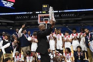 Kimball’s head coach Nicke Smith holds up the trophy as Kimball team members and fans...