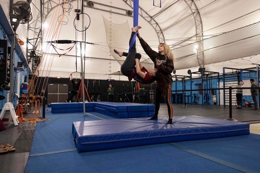 Amber Holtz (right), hammock instructor, assists Jaimie Yang, of Dallas, while performing a...
