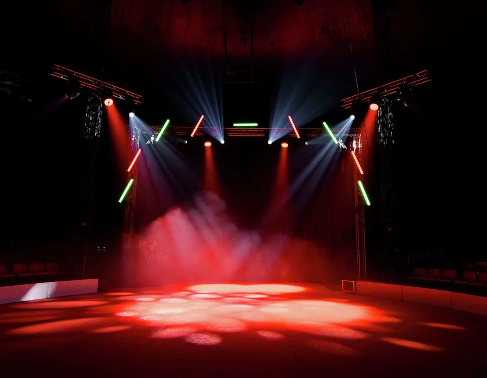 Colorful stage lights illuminating empty circus arena with smoke effects. (Lamina Akulova/Getty Images)