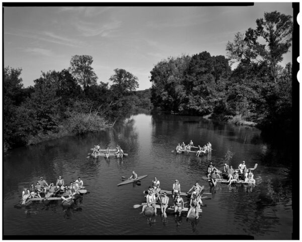 A black and white photograph of people floating on river rafts.