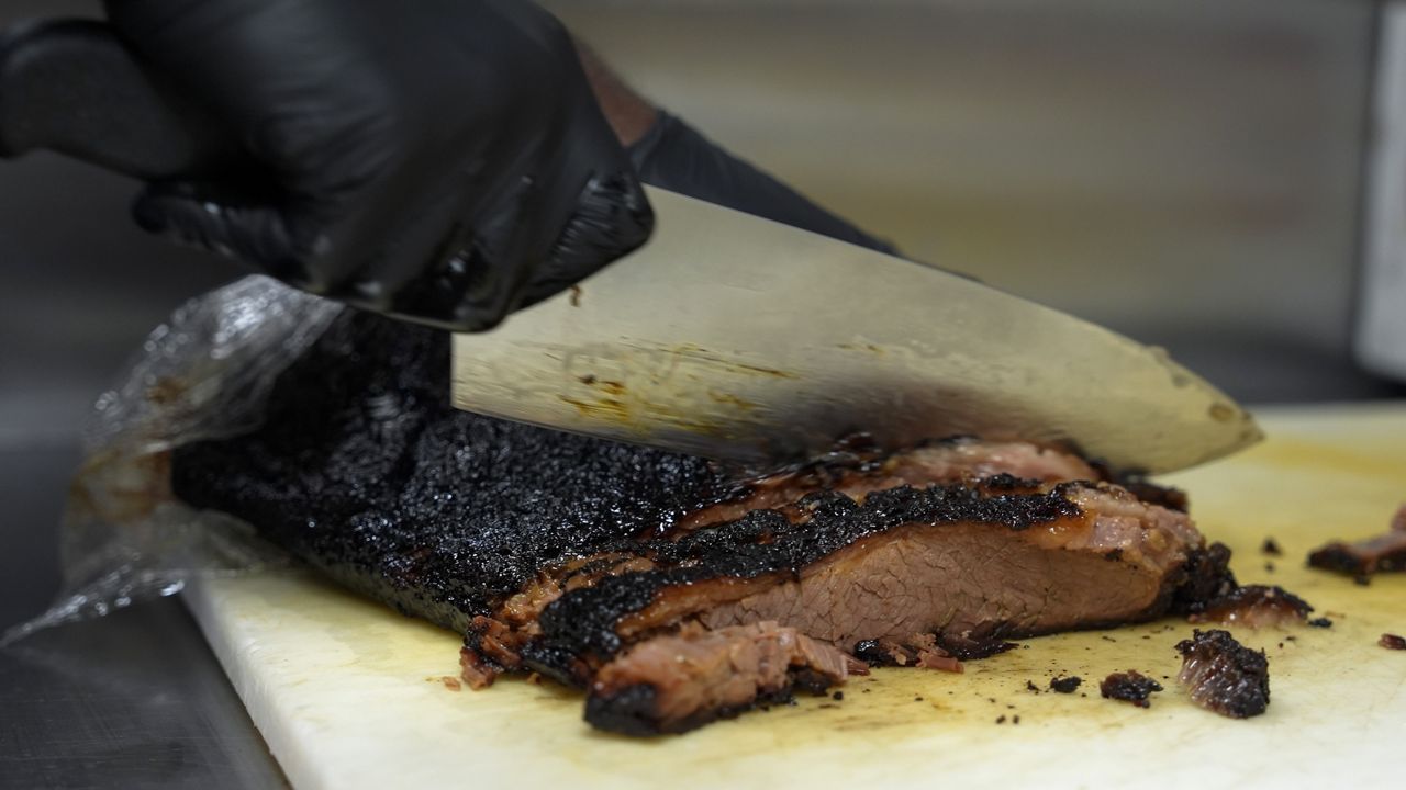 A line cook slices beef brisket, Wednesday, June 12, 2024, at a barbecue restaurant in Cincinnati. (AP Photo/Joshua A. Bickel)