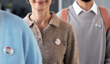 A picture of people wearing election buttons waiting in line to file documents.
