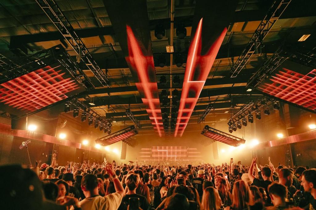 A crowd in a nightclub illuminated by red and yellow lights.
