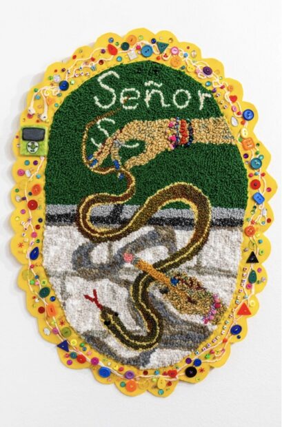 An ovular tufted textile artwork featuring a hand holding a snake and the word "Señor."