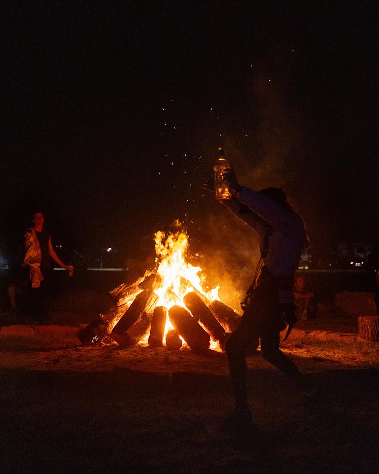 People gather around a bonfire after the end of the first day of the festival. Under new ownership, rules have been implemented to tame the activities that are infamous at the renaissance fair's campground.