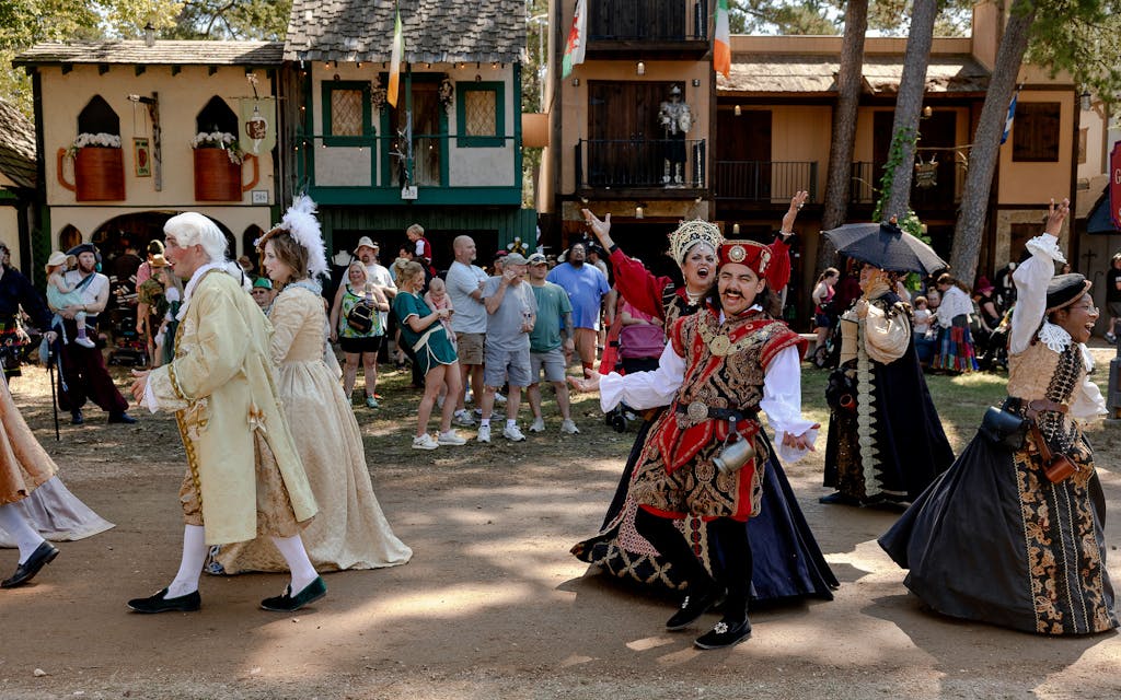 Performers cheer to the crowd as they walk through the fairgrounds in a parade.