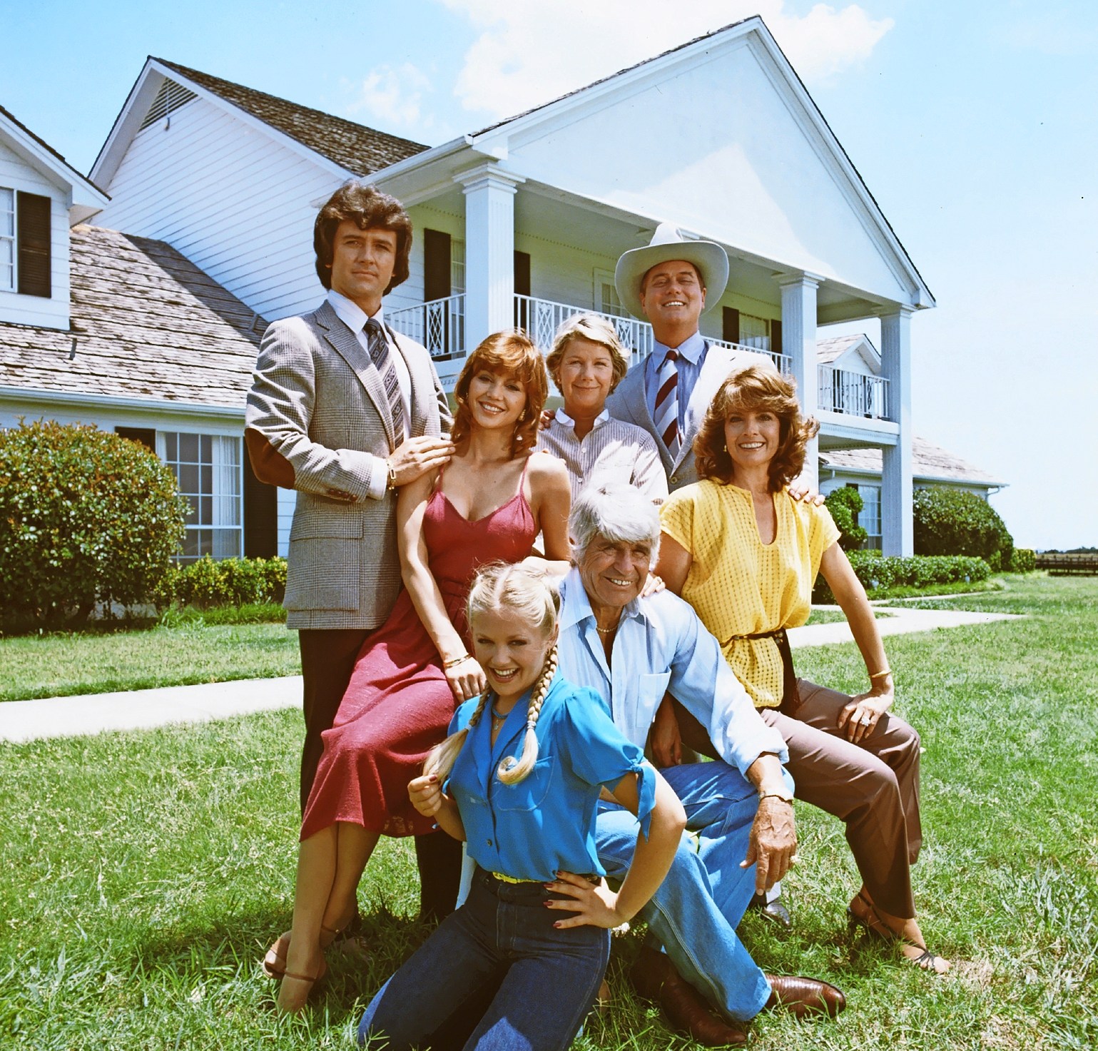 Promotional still of the cast of "Dallas" in front of the Southfork Ranch.