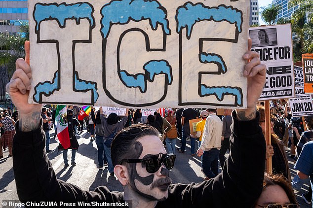 A protester holds a sign at a demonstration calling for an end to federal immigration enforcement operations