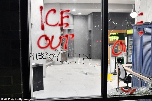 Graffiti and a shattered glass window are seen while protesters participate in the 'ICE OUT! Noise Demo' at the hotel